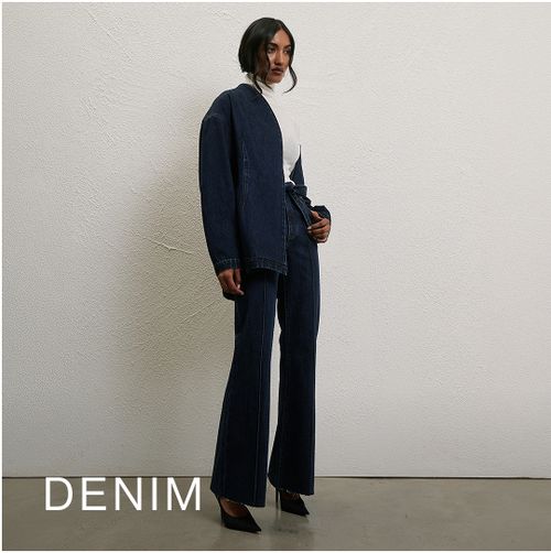 Model wearing a dark denim jacket and jeans. SHOP DENIM.