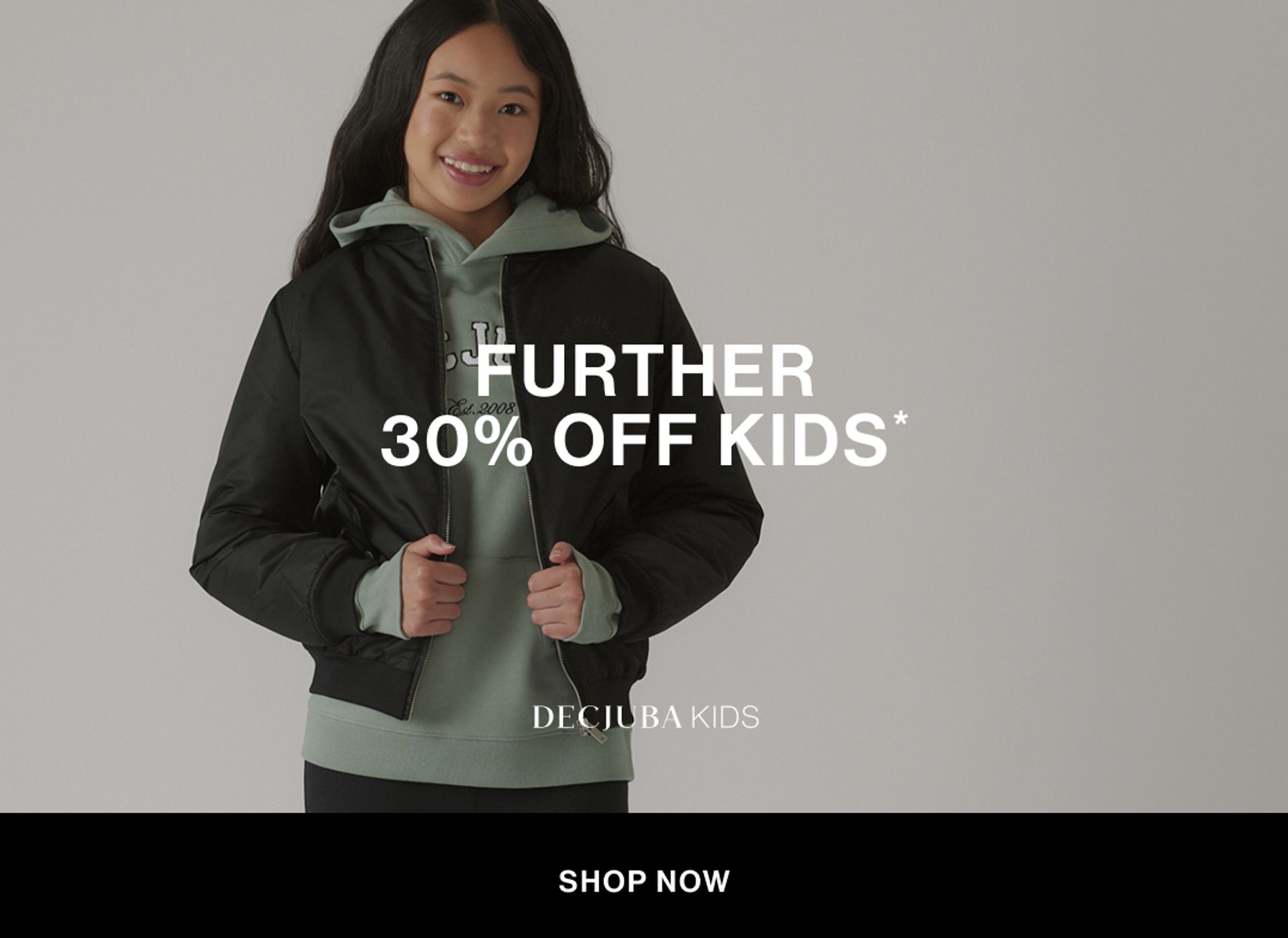 Model wearing a green hoodie and black bomber in a studio. Text reads FURTHER 30% OFF KIDS.