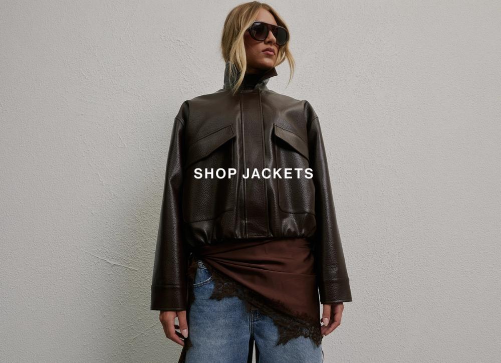 Model wearing a brown leather jacket layered over a top and jeans.