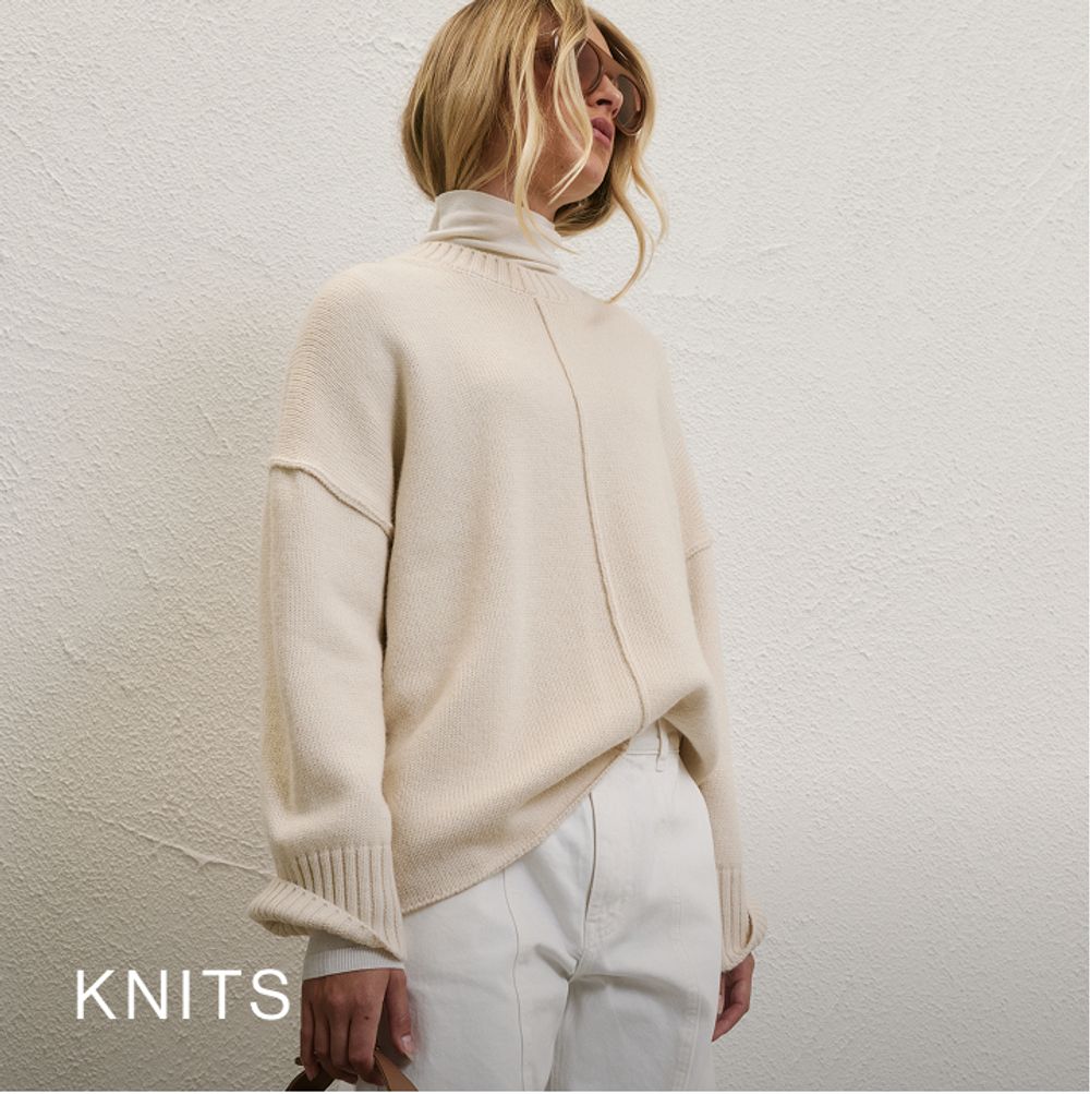 Model wearing a white knit jumper. SHOP KNITS.