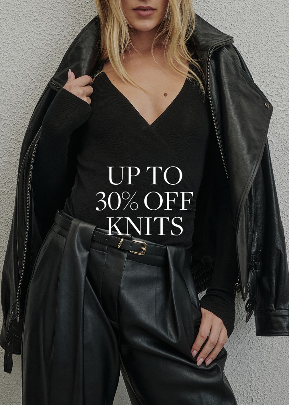 Model wearing a black knit. SHOP KNITS.