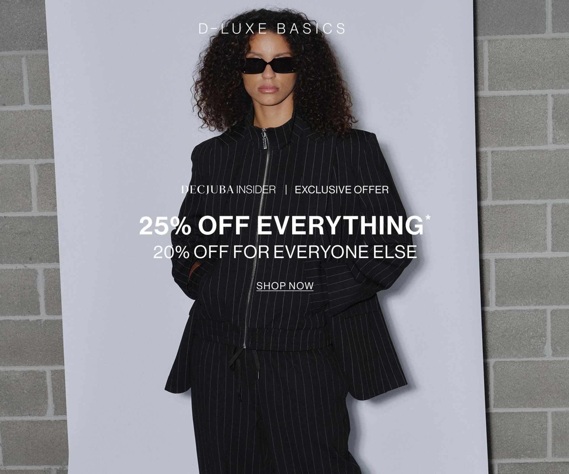 Model wearing black pinstripe suit against a neutral background. SHOP NEW 25% OFF D-LUXE.