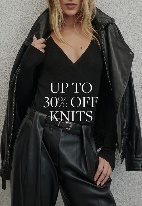 Model wearing a black knit. SHOP KNITS.