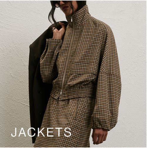 Model wearing a check print jacket and skirt. SHOP JACKETS.