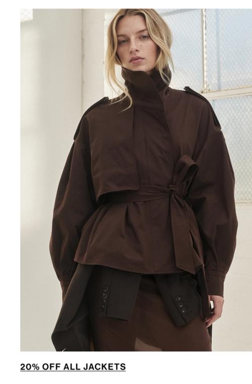 Model posing in a brown cropped trench jacket. SHOP JACKETS.