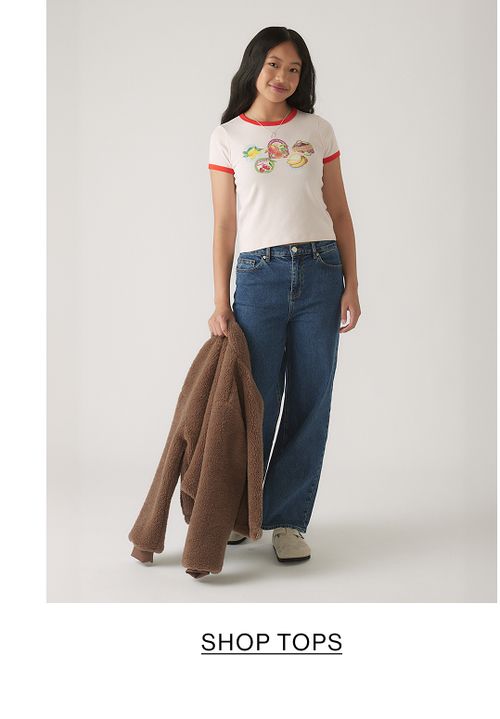 Girl wearing a white t-shirt with text that states shop tops