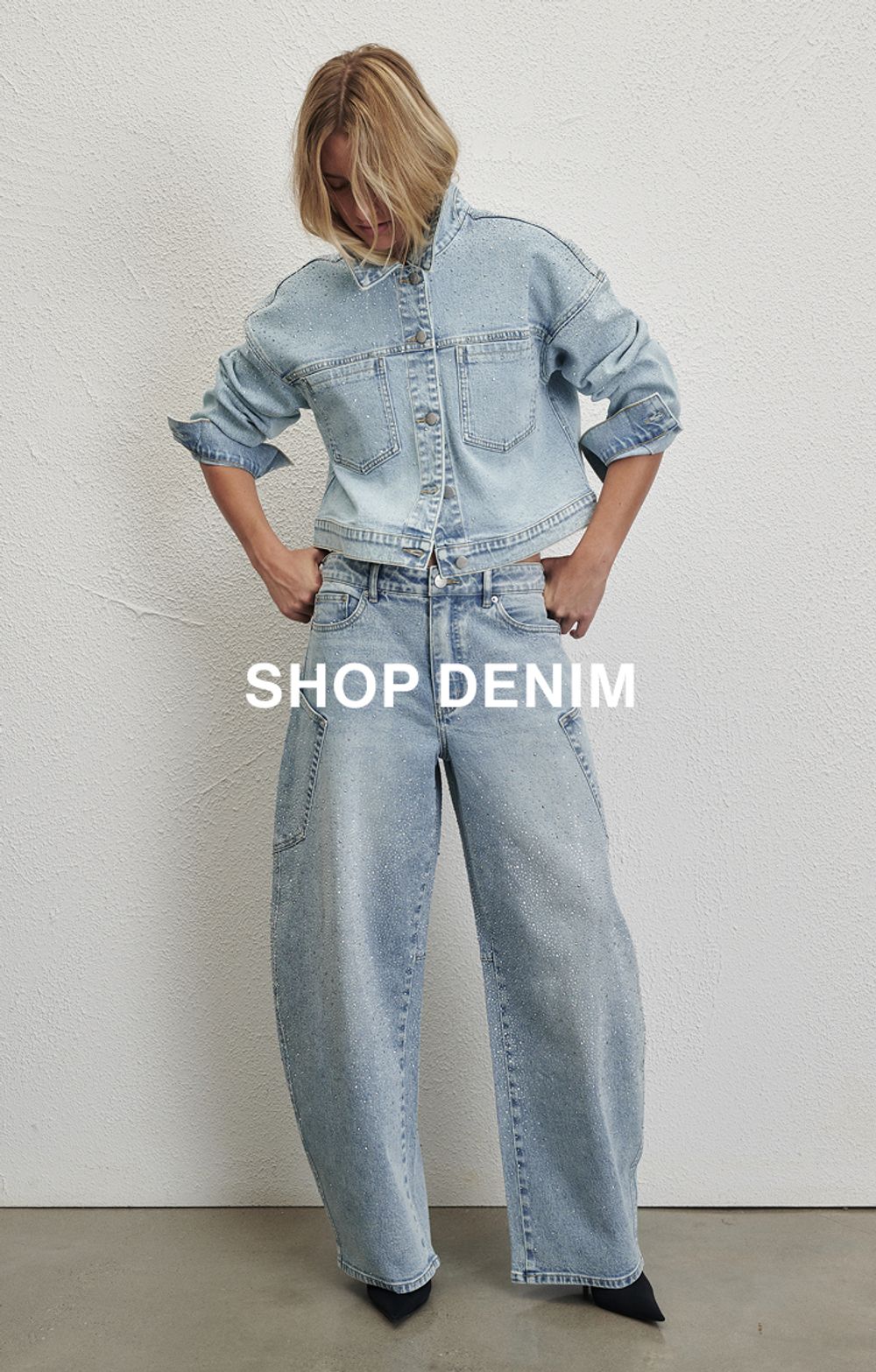 Model wearing sparkly denim jeans. Text reads SHOP DENIM