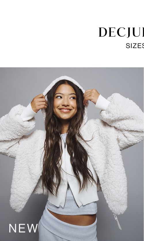 Young girl wearing a fluffy white hood with grey tracksuit pants. SHOP NEW TEEN.