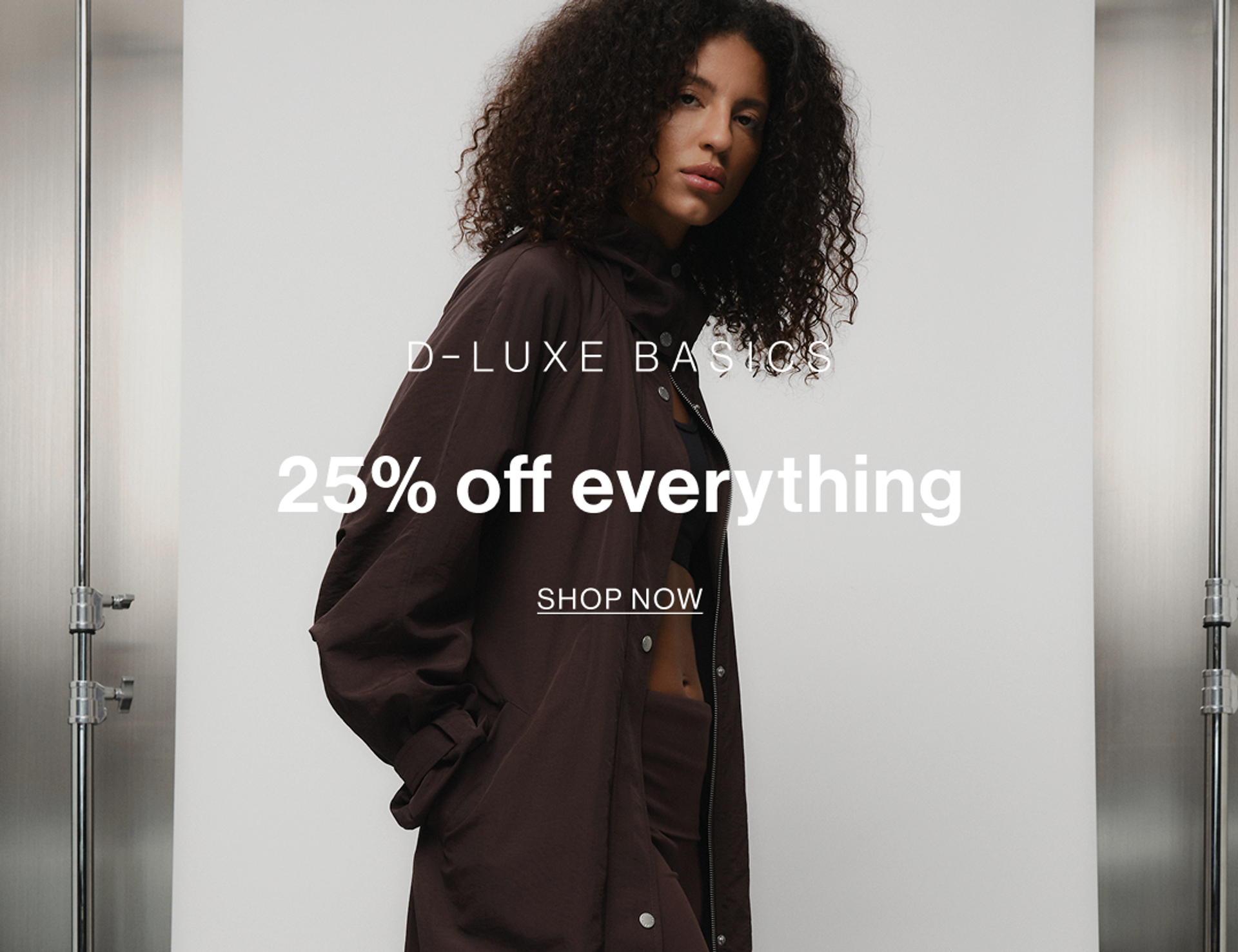Model wearing brown shirt and trousers set, promoting D-Luxe Basics collection with 25% off.