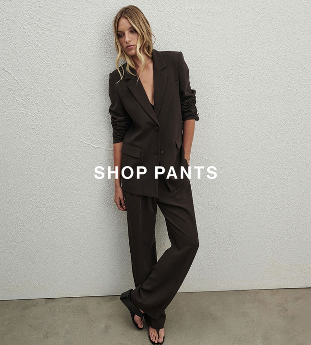 Model in a tailored dark brown pantsuit and heels – Shop Pants.