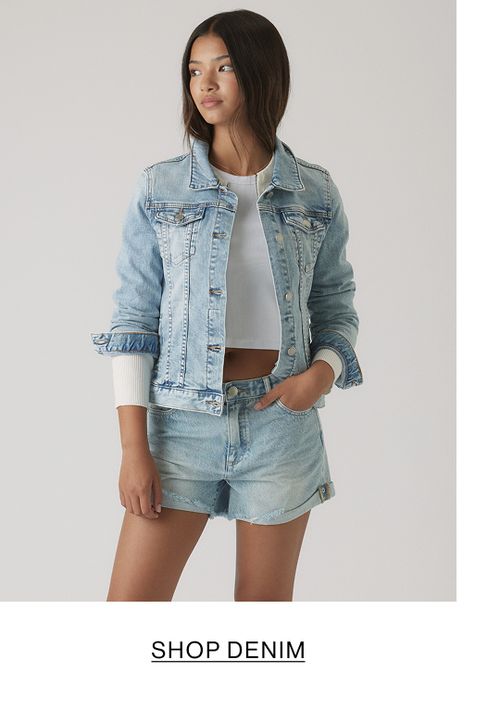 Young girl wearing a light denim short-sleeve shirt layered over a white top with matching denim shorts.