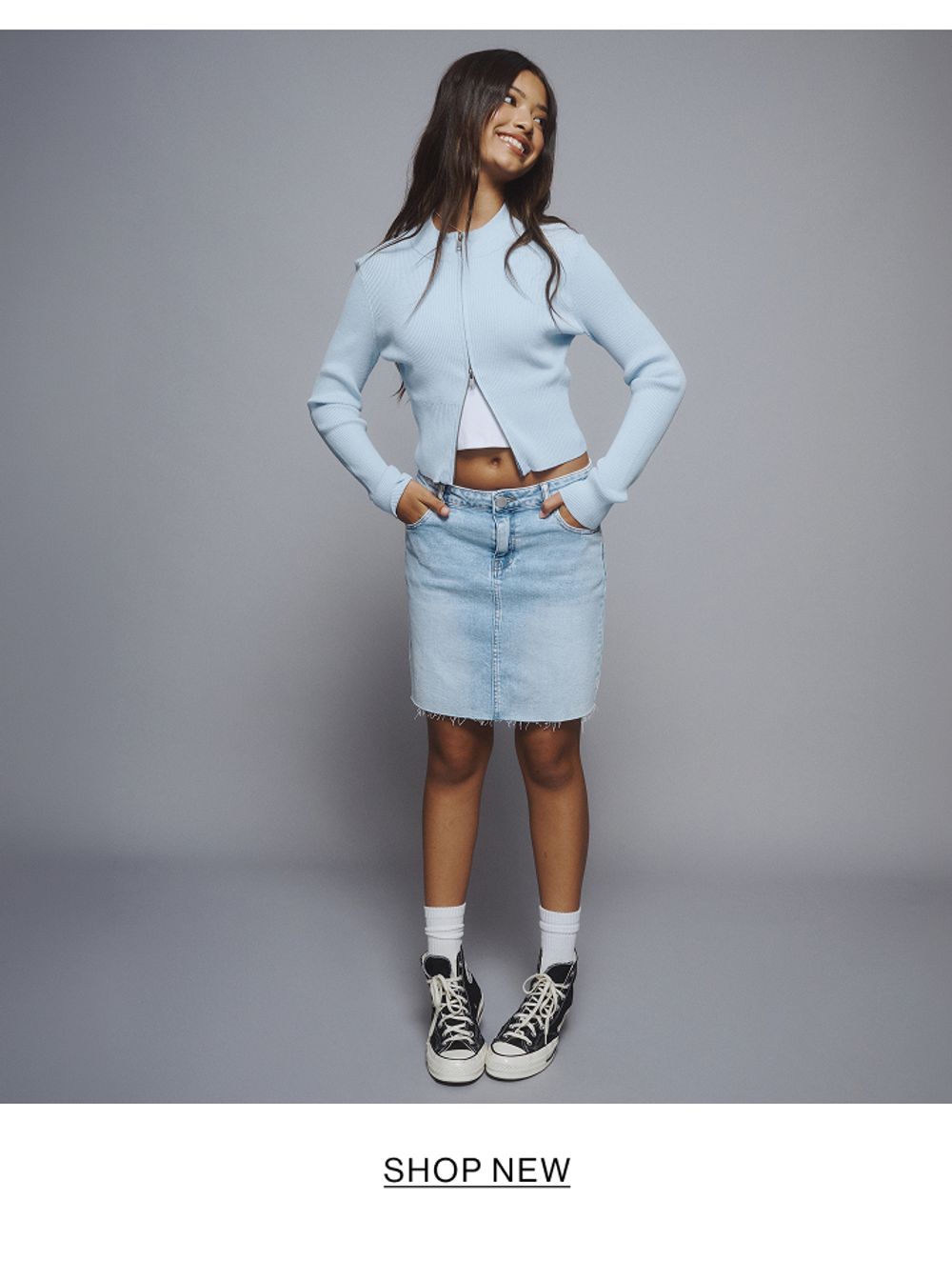 Young girl wearing a light blue denim jacket and skirt set.