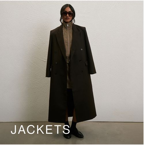 Model wearing a brown blazer coat against a neutral background. SHOP JACKETS.