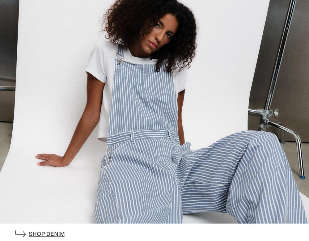 Model posing wearing blue denim overalls