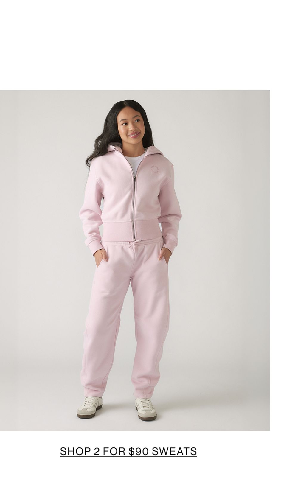 Model wearing a matching pink set with text that states shop 2 for $90 sweats