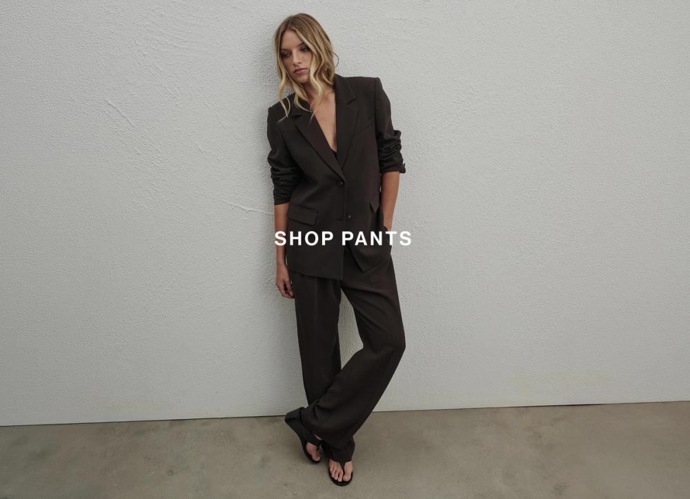 Model in a tailored dark brown pantsuit and heels – Shop Pants.