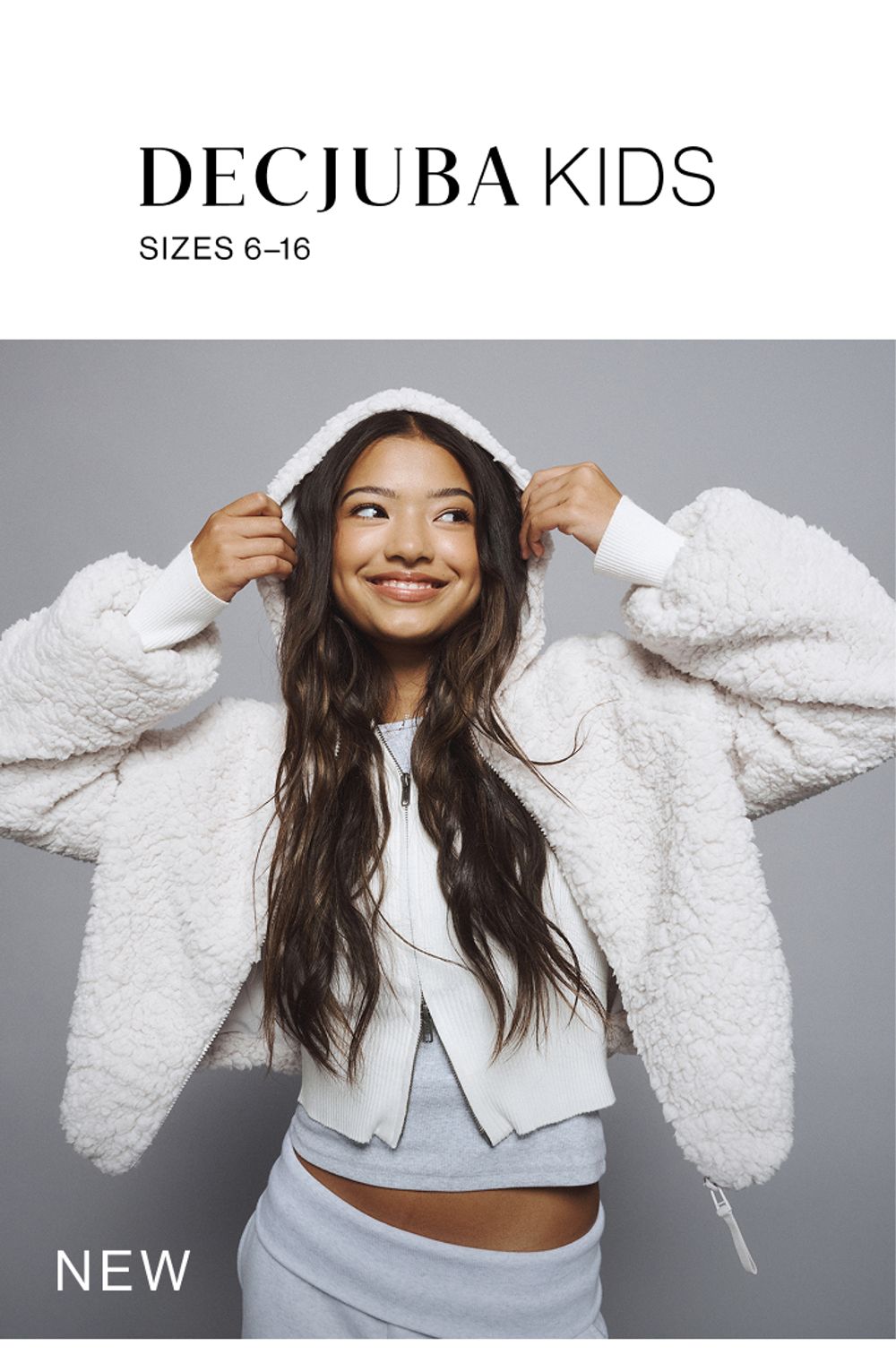 Young girl wearing a fluffy white hood with grey tracksuit pants. SHOP NEW TEEN.