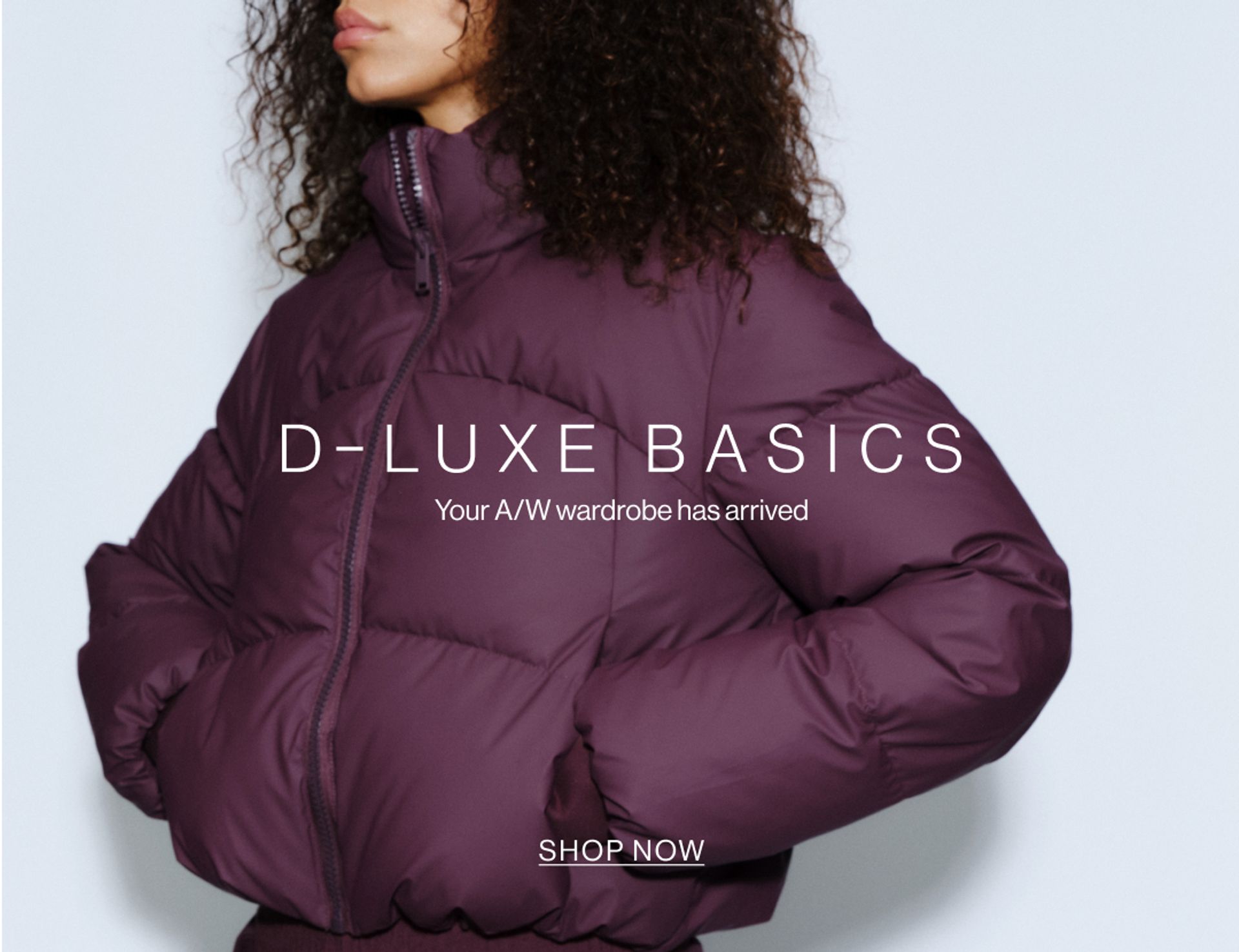Model wearing a puffer jacket in midnight cherry in a studio. SHOP NEW D-LUXE.