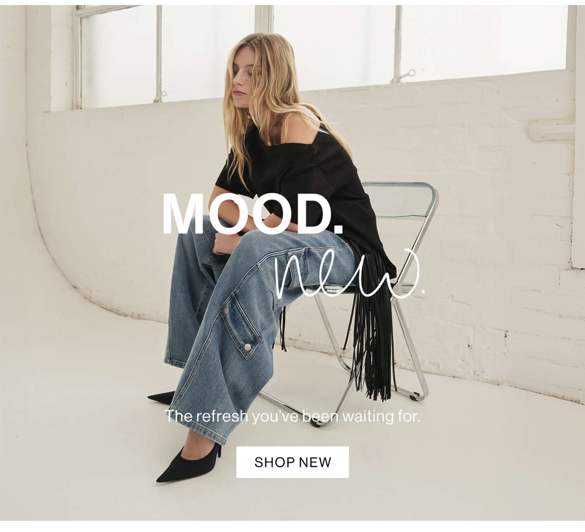 Model sitting in chair posing in off shoulder black tee and blue cargo jeans with text overlay: "MOOD. New."