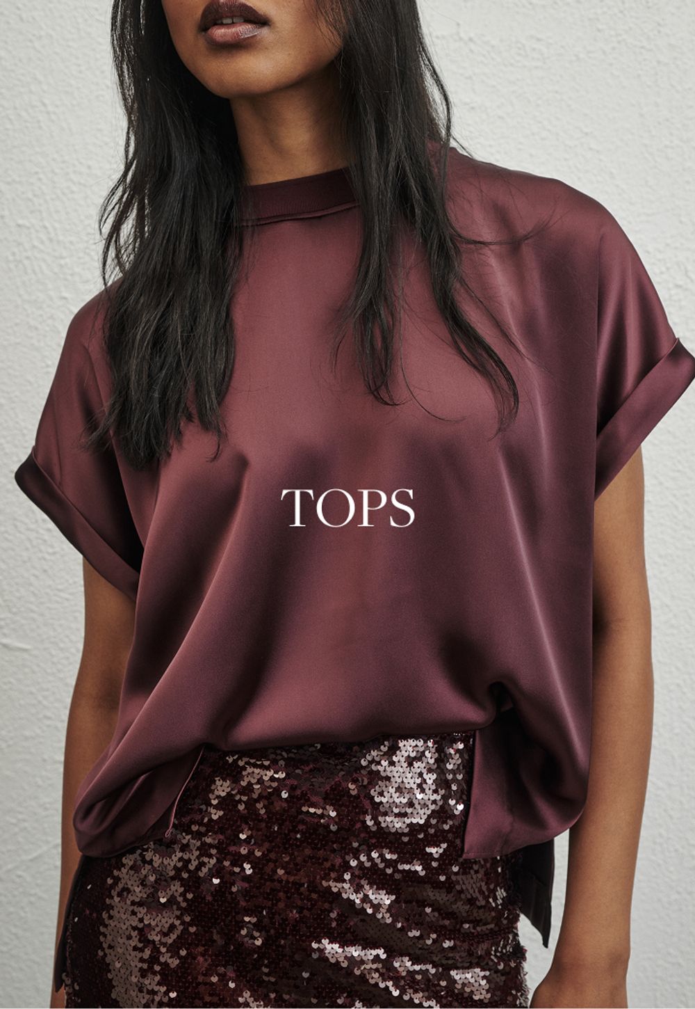 Model wearing a black long sleeve top. SHOP TOPS.