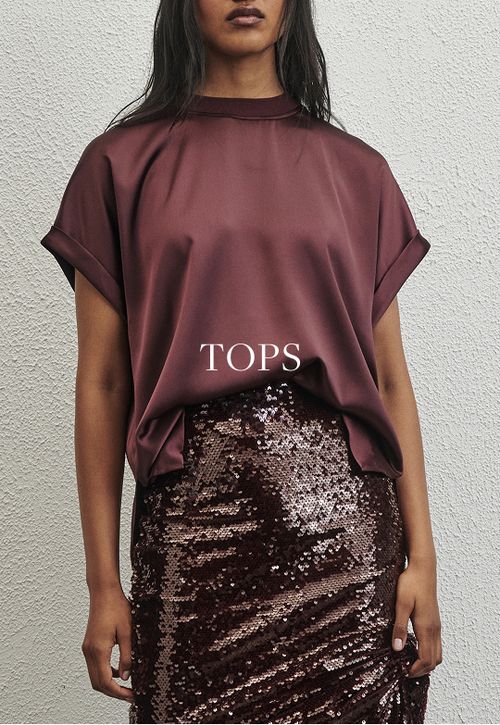 Model wearing a plum satin tee and sequin skirt. SHOP TOPS.
