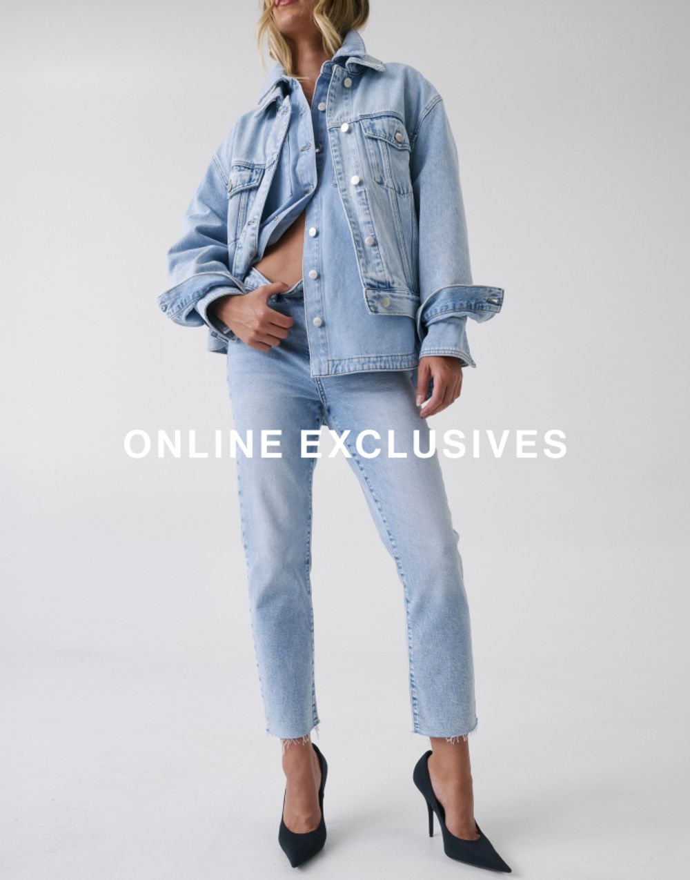 Jess Hart standing in blue slim-fit jeans with a cropped blue jacket, hand in pocket. SHOP ONLINE EXCLUSIVES
