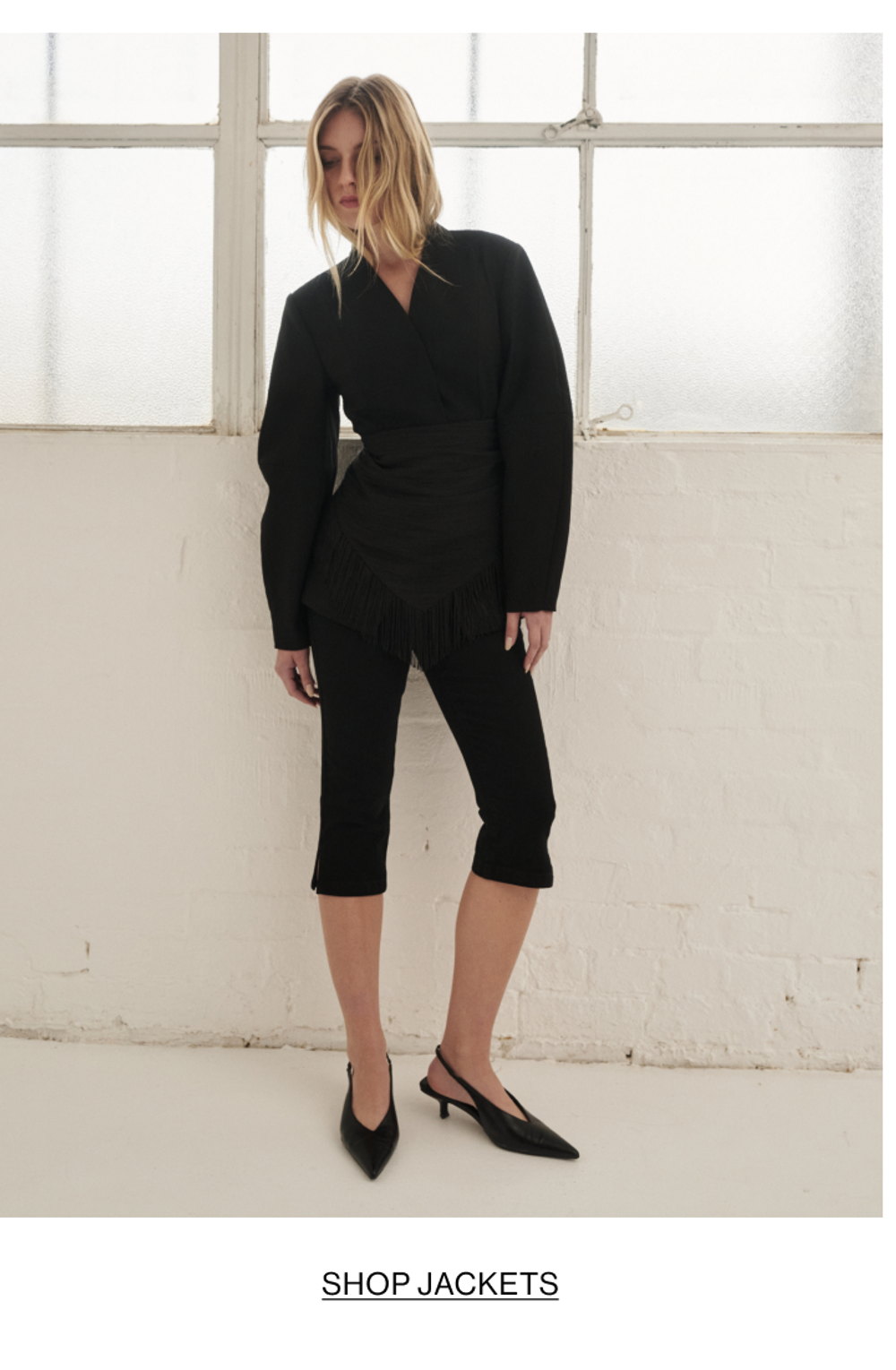 Model posing in a cinched blazer in black. SHOP JACKETS.
