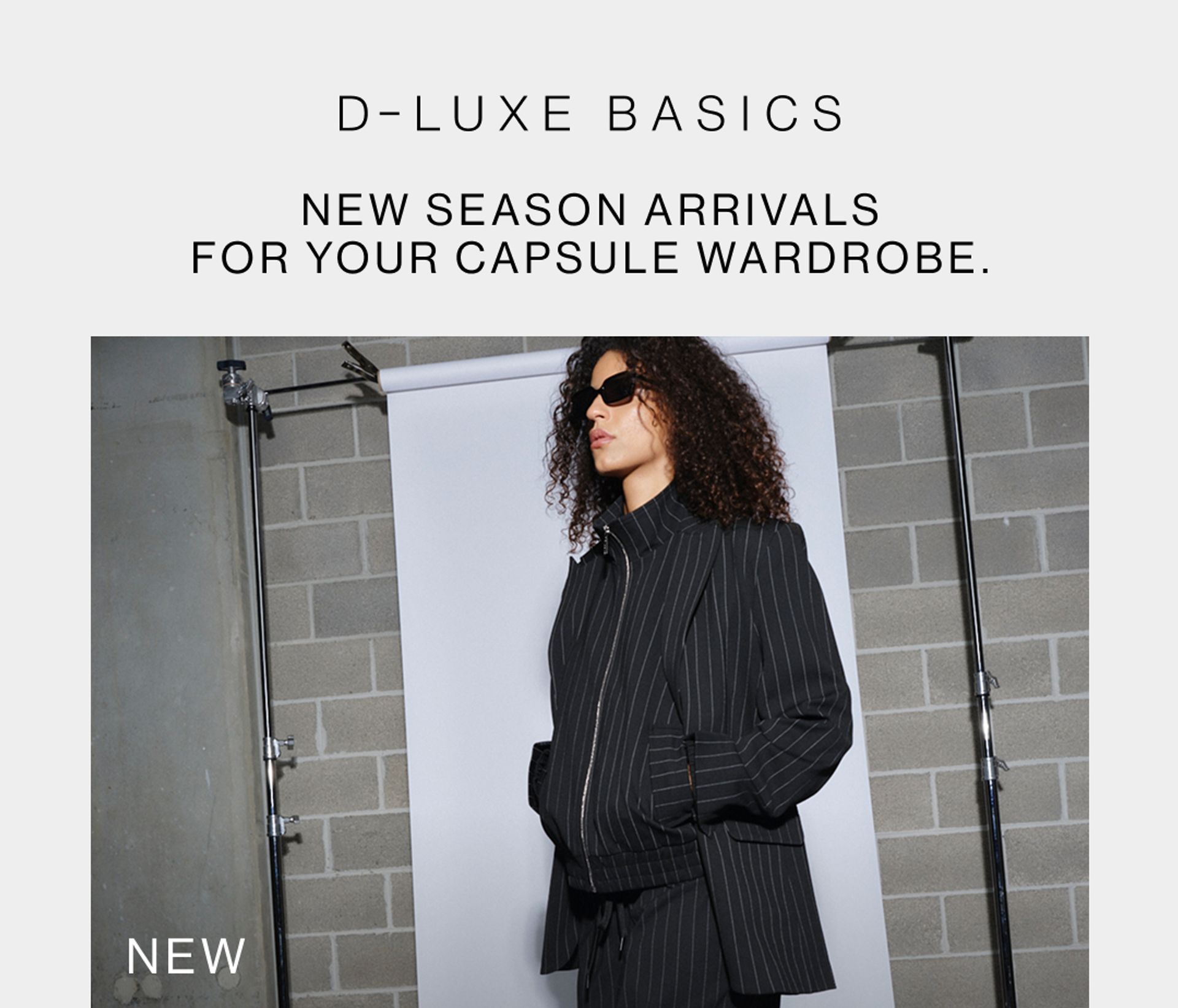 Model wearing black pinstripe suit in a studio. SHOP NEW D-LUXE.