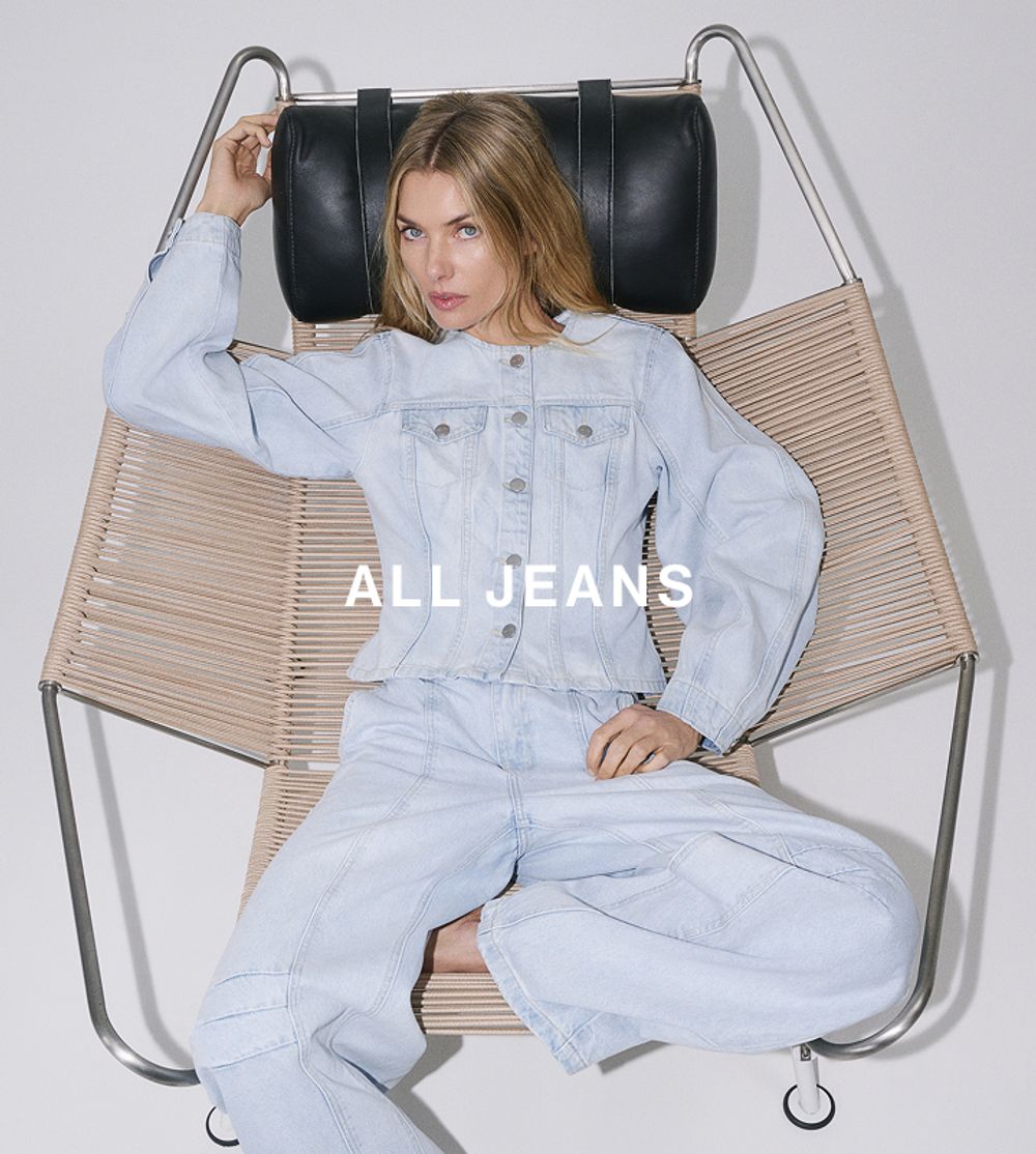 Model lounging in a hanging chair wearing light wash jeans – All Jeans category.