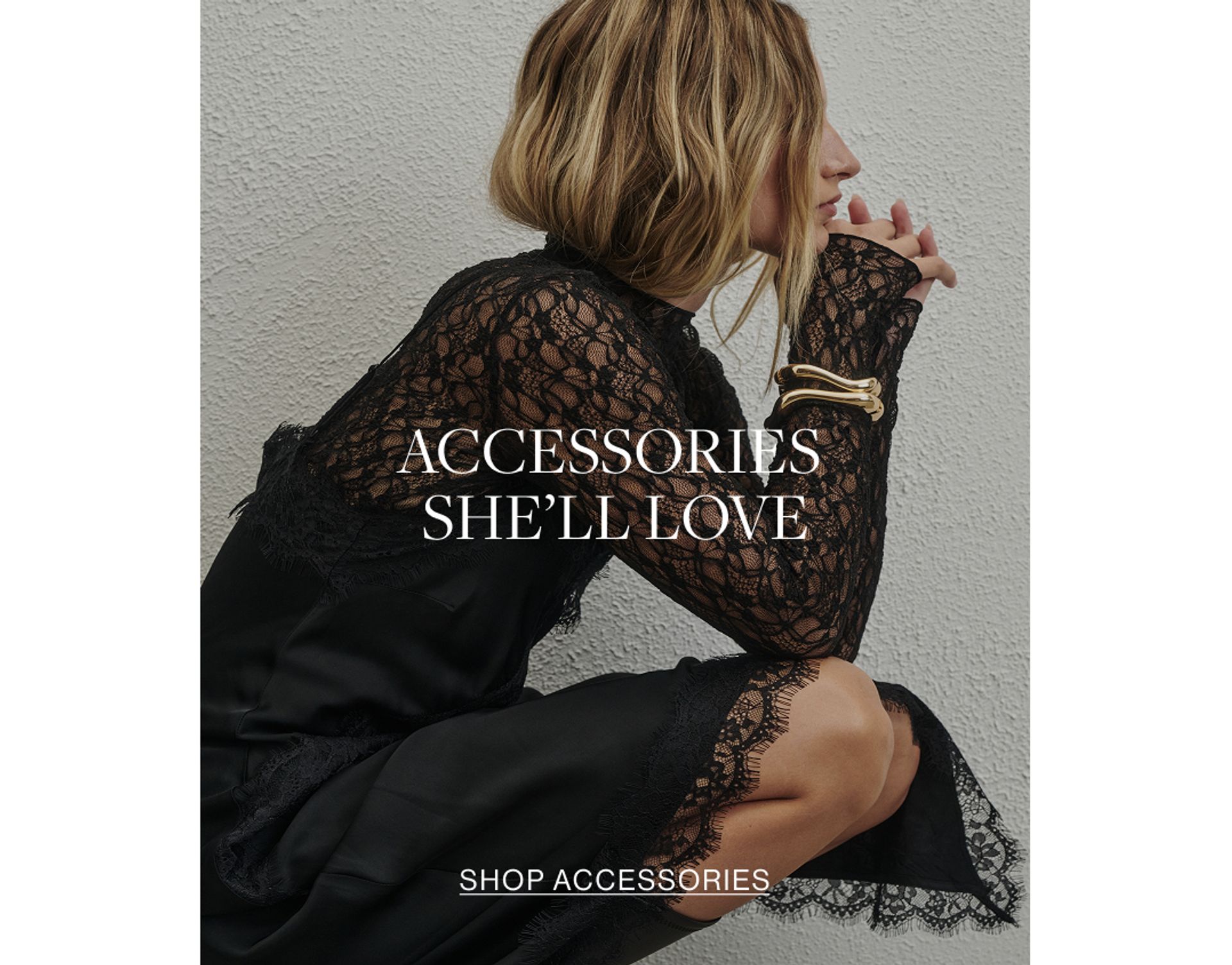 Close up shot of model wearing a black lace long sleeve top with a gold bangle with text overlay: "ACCESSORIES SHE'LL LOVE"
