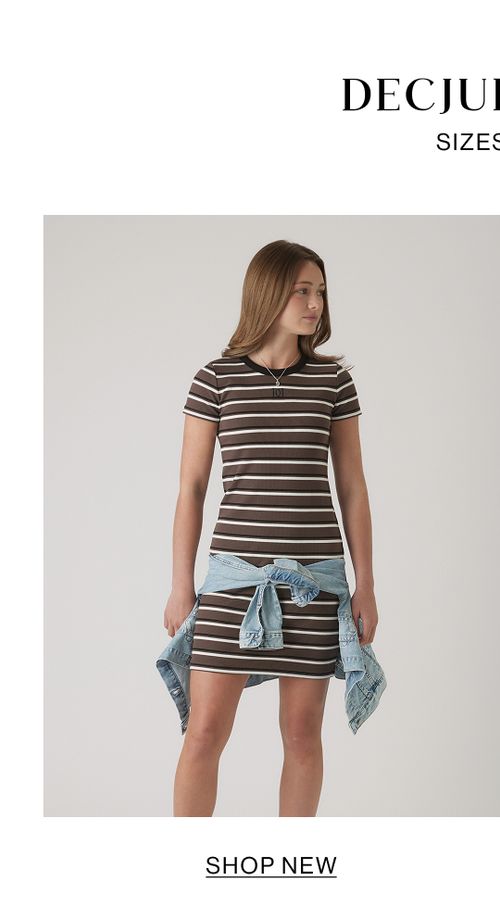 Young girl wearing a brown and cream striped short-sleeve tee with light denim tied around her waist, standing against a neutral background.