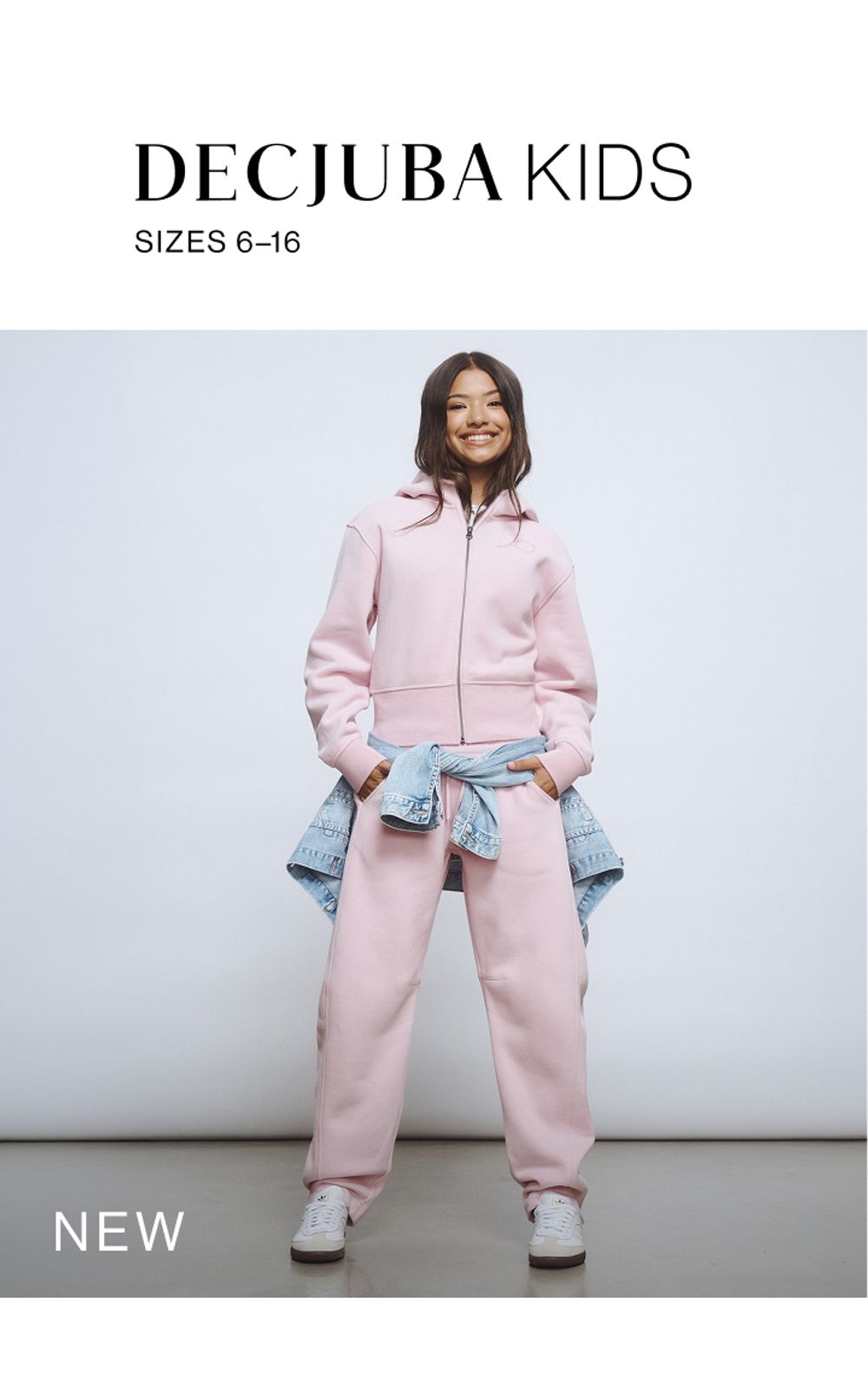 Young girl wearing a light pink sweat tracksuit set. SHOP NEW TEEN.