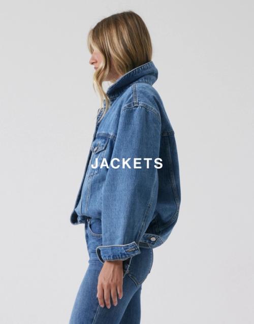 Side profile of model wearing a classic blue denim jacket with a high collar. SHOP DENIM JACKETS.