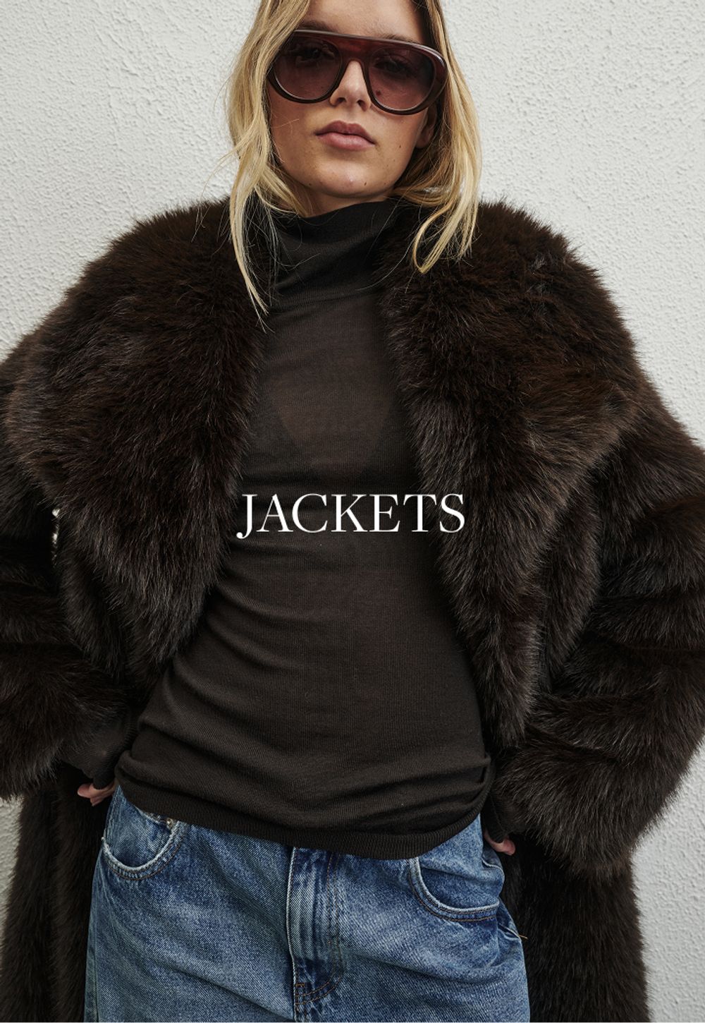 Model wearing a brown faux fur jacket. SHOP JACKETS.