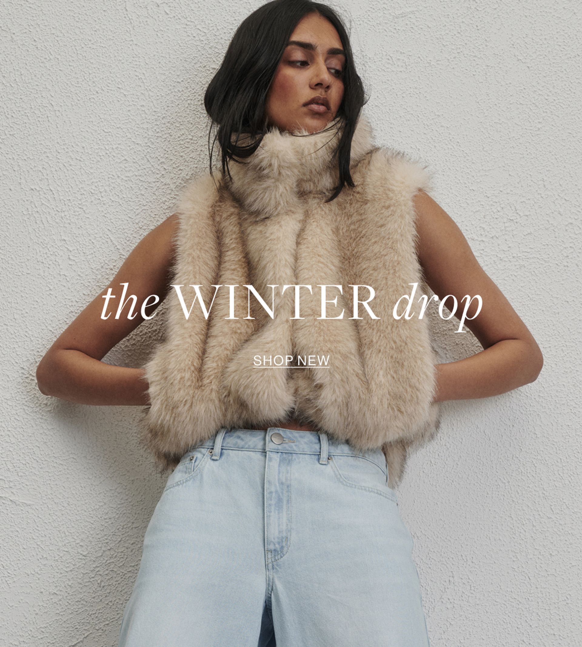 Woman posing in front of a white wall wearing a neutral Gilet with text the states "The winter drop shop now"