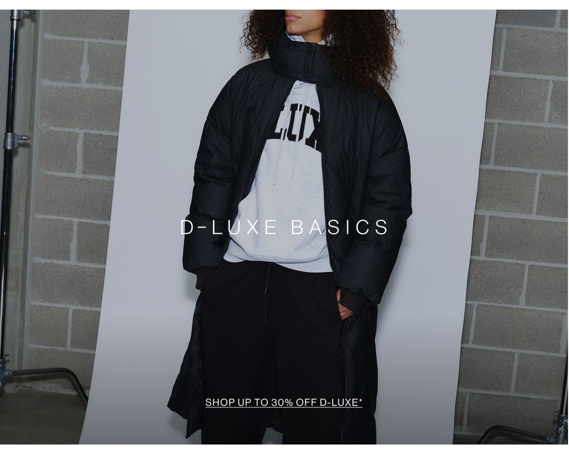 Model wearing a puffer jacket in midnight cherry in a studio. SHOP NEW D-LUXE.