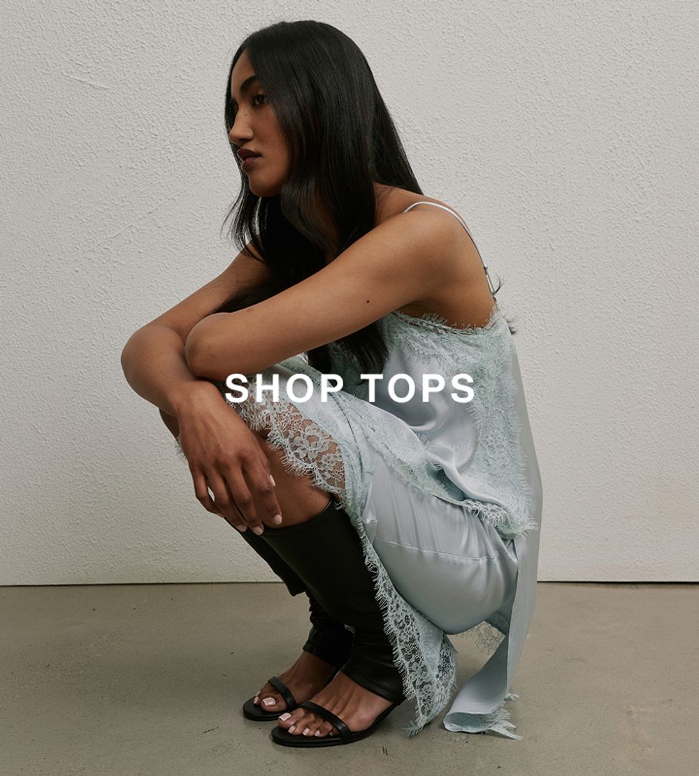 Model crouching in a light blue sleeveless top and matching skirt.