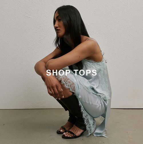 Model crouching in a light blue sleeveless top and matching skirt.