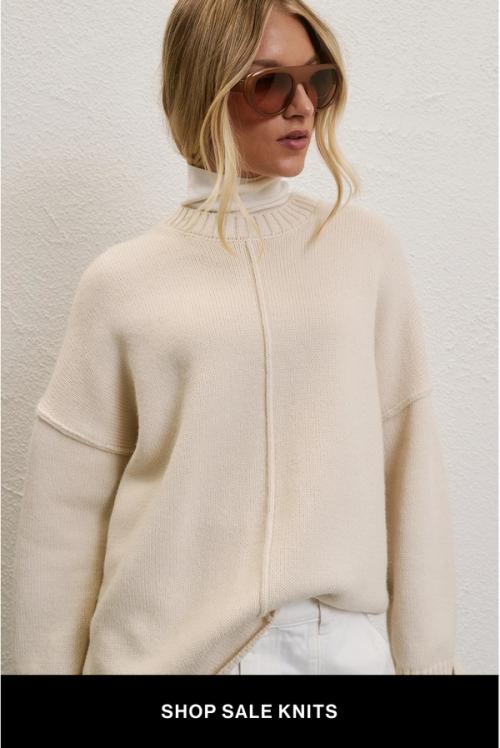 A model wearing a cream knit against a neutral background. SHOP SALE KNITS.