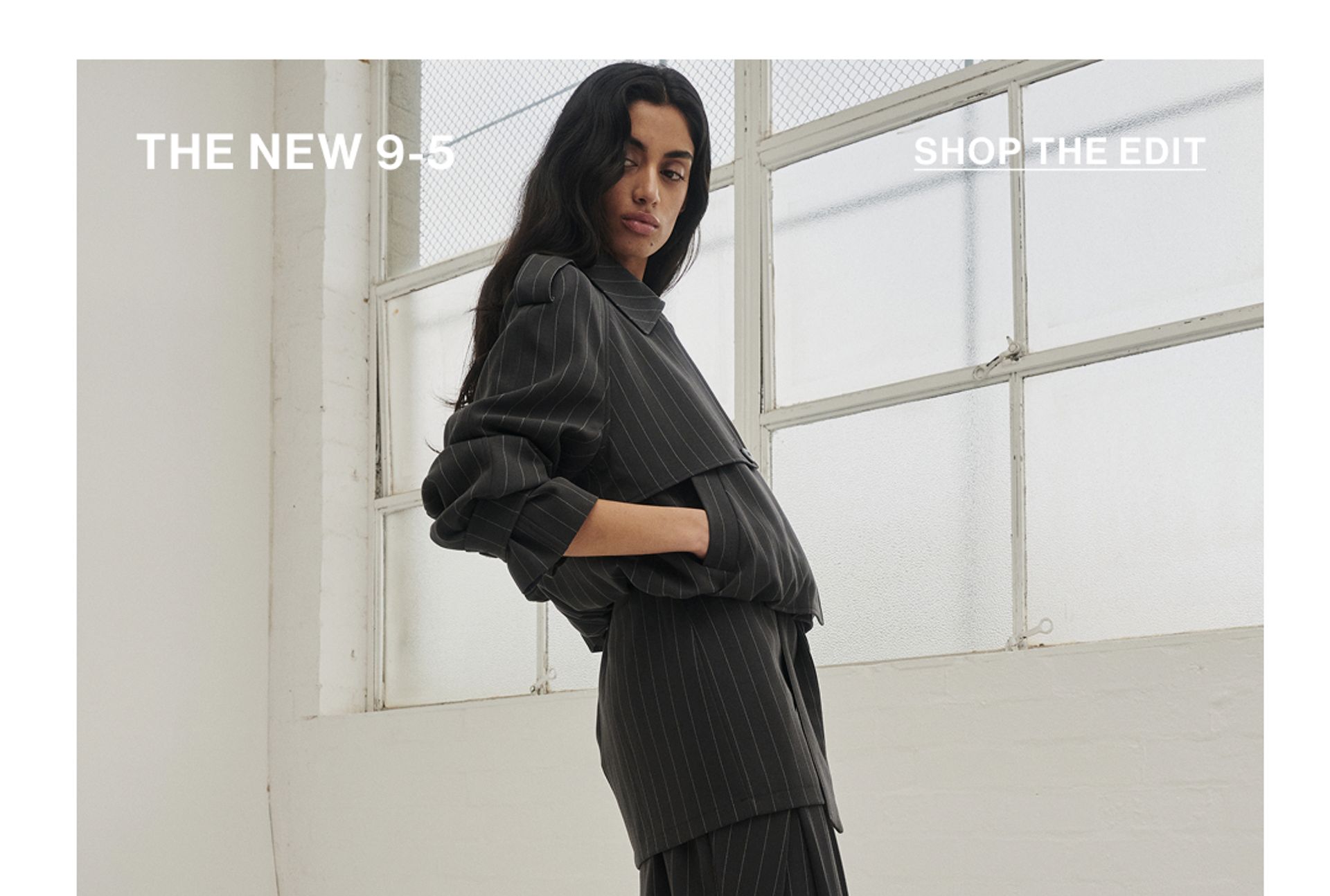 Model standing with hand in her pockets wearing an almond cropped trench jacket with text overlay: "THE NEW 9-5""