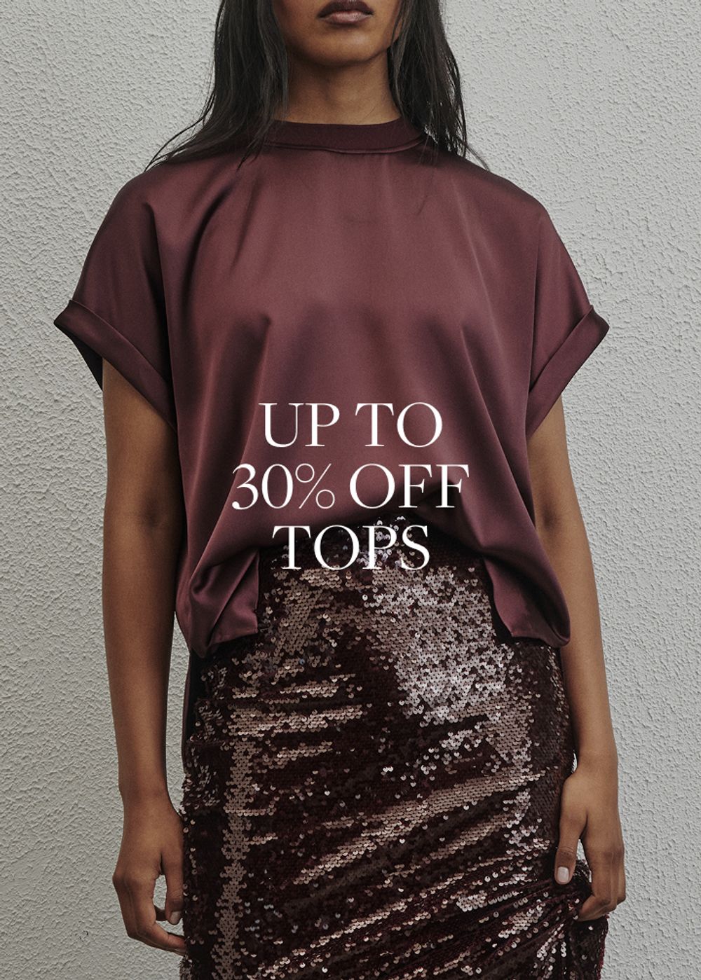 Model wearing a black long sleeve top. SHOP TOPS.