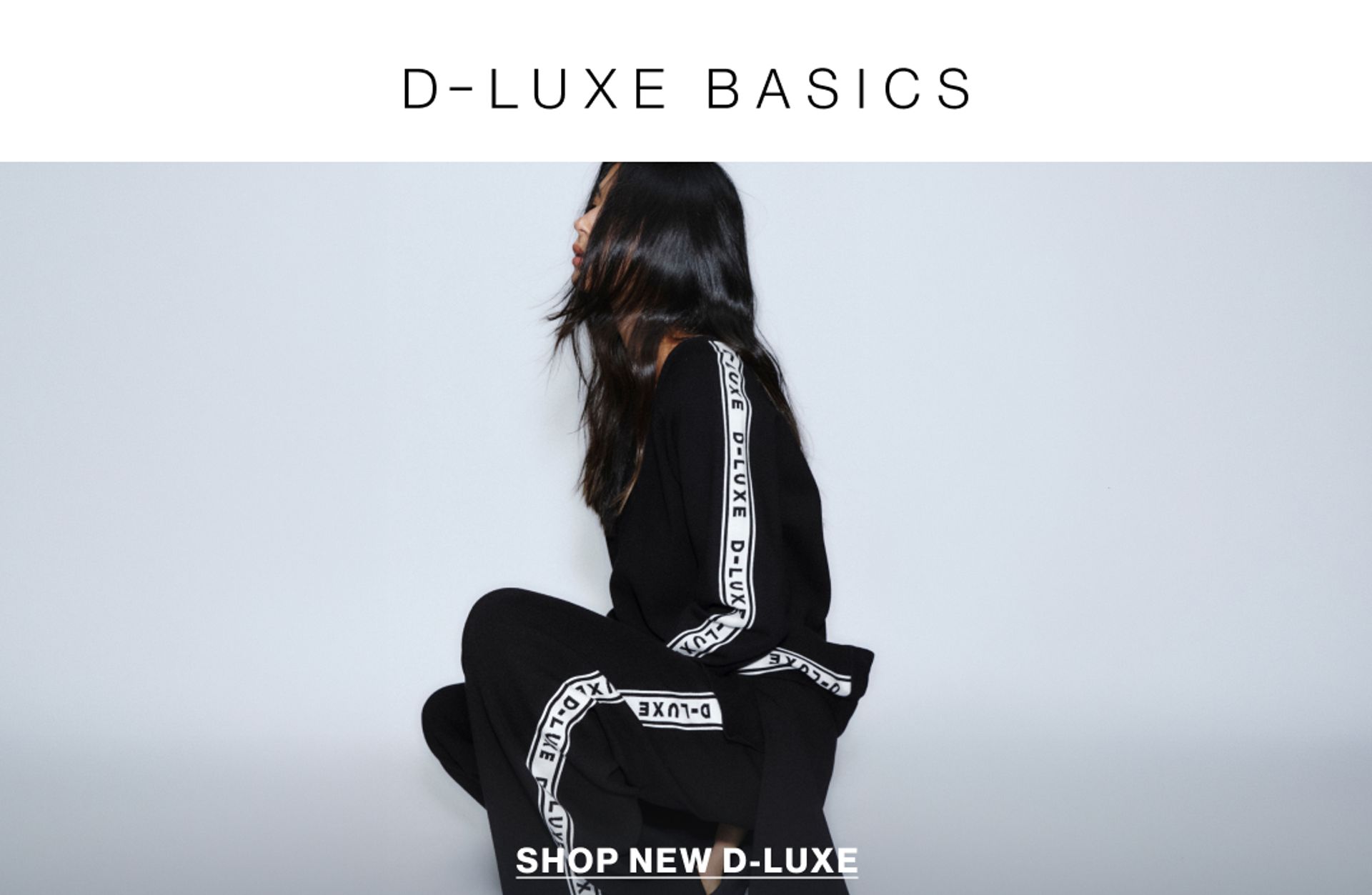 Model wearing a black knit with white logo branding in a studio. Text reads D-LUXE BASICS