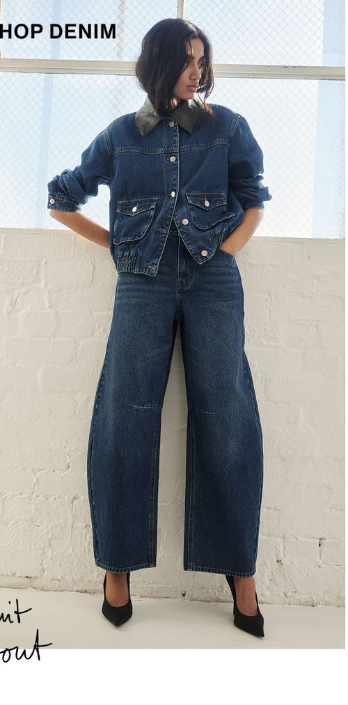 Model posing in a blue denim set in a studio. SHOP DENIM.