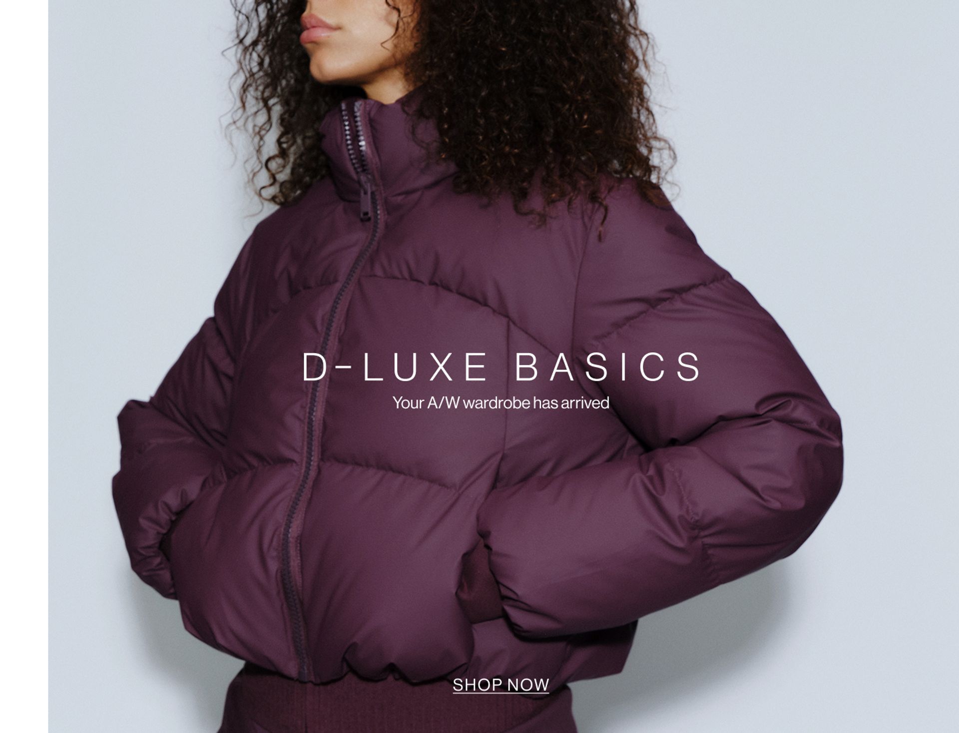 Model wearing a puffer jacket in midnight cherry in a studio. SHOP NEW D-LUXE.