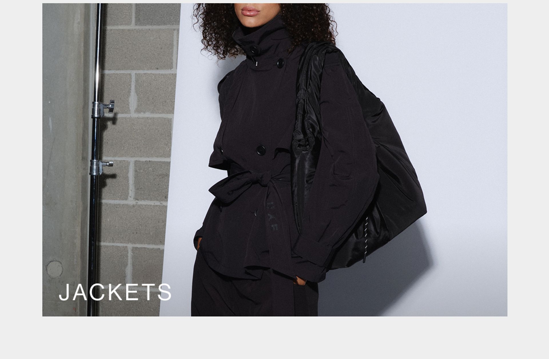 Model wearing a black high neck jacket in studio. SHOP D-LUXE JACKETS.