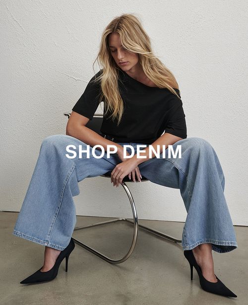 Model sitting wearing a black off shoulder top and denim jeans. Text reads SHOP DENIM