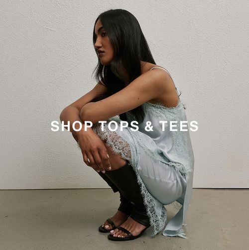 Model crouching in a light blue sleeveless top and matching skirt.