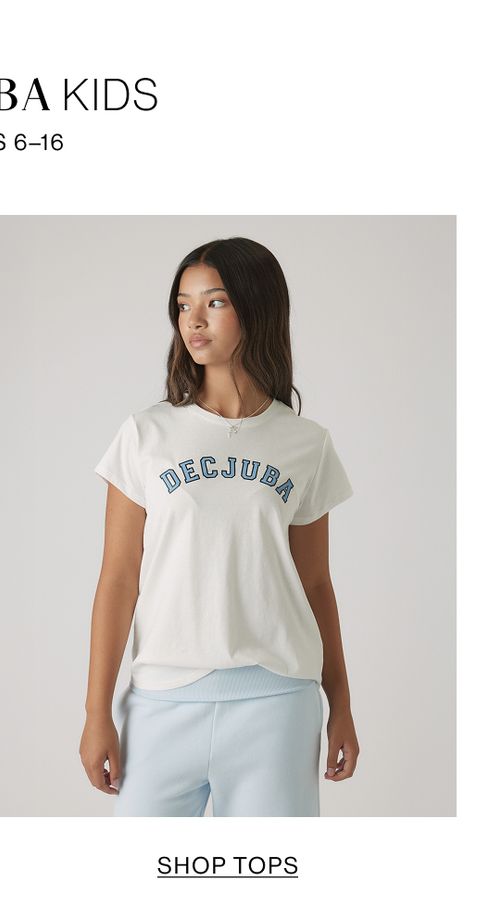 Young girl wearing a white graphic T-shirt with blue DECJUBA lettering, posing against a soft neutral backdrop.