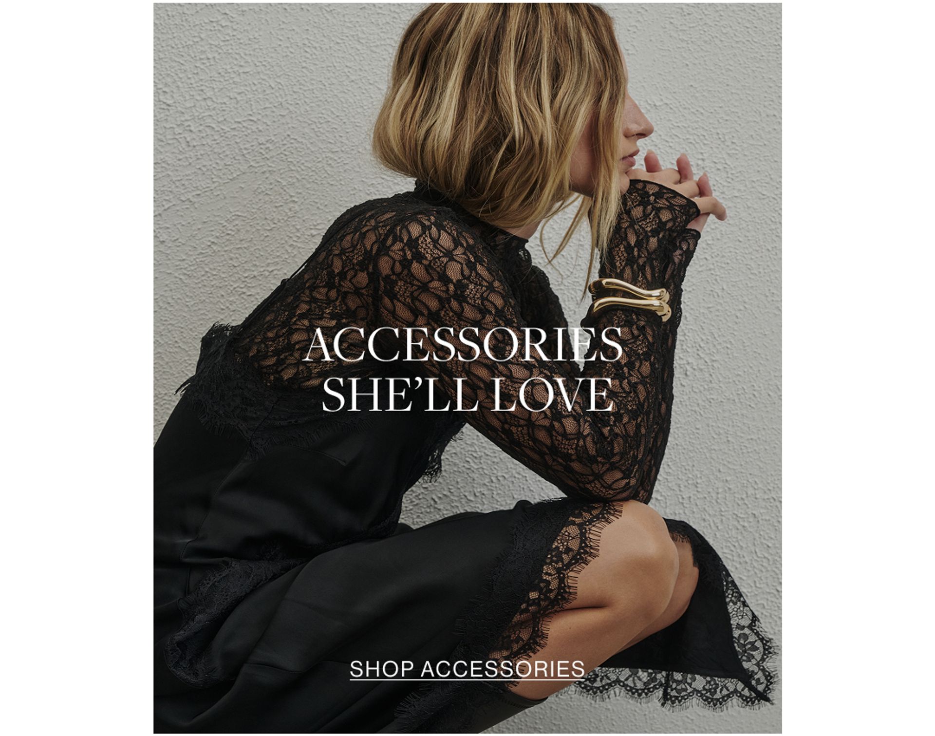 Close up shot of model wearing a black lace long sleeve top with a gold bangle with text overlay: "ACCESSORIES SHE'LL LOVE"