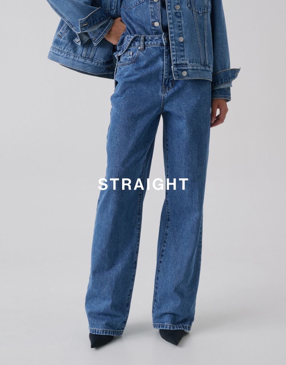Jess Hart standing in classic straight-leg blue jeans and denim shirt. SHOP STRAIGHT LEG JEANS.